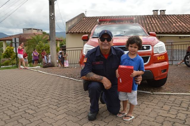 Sargento Pujol entregando brinquedo para o menino Matheus Henrique, de 3 anos